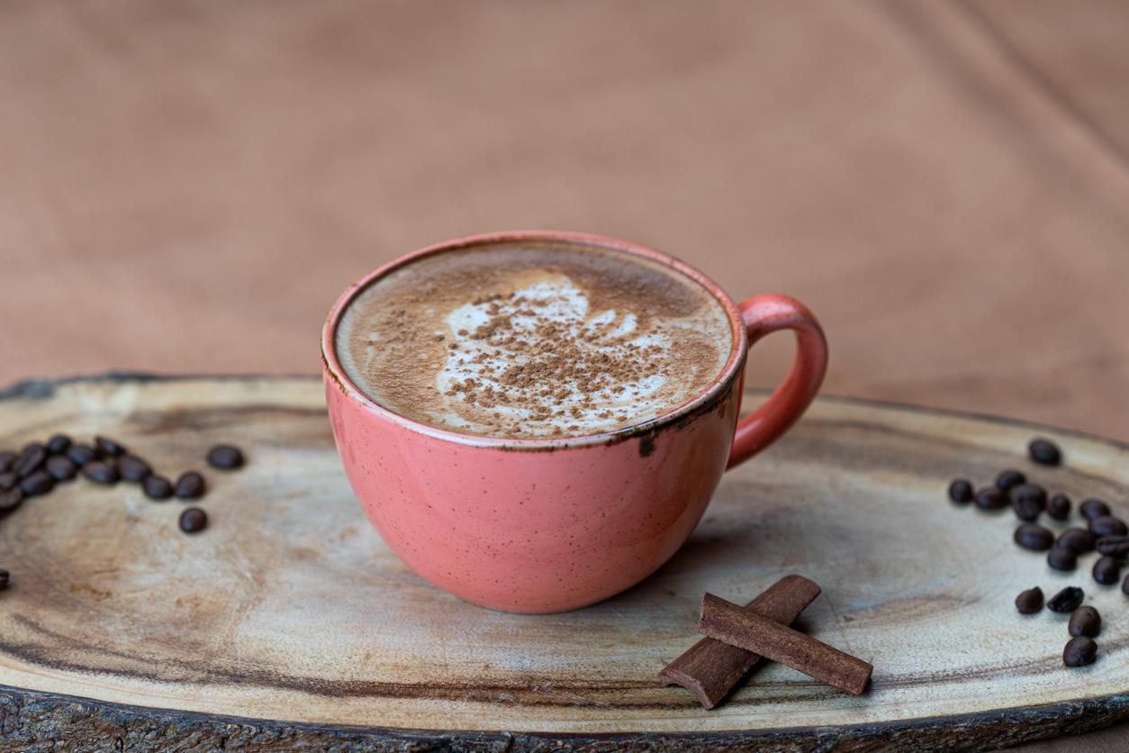 A hot chai latte with cinnamon on top in a round, red mug.