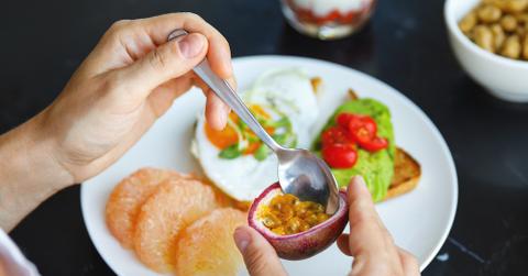 A person eating passion fruit.