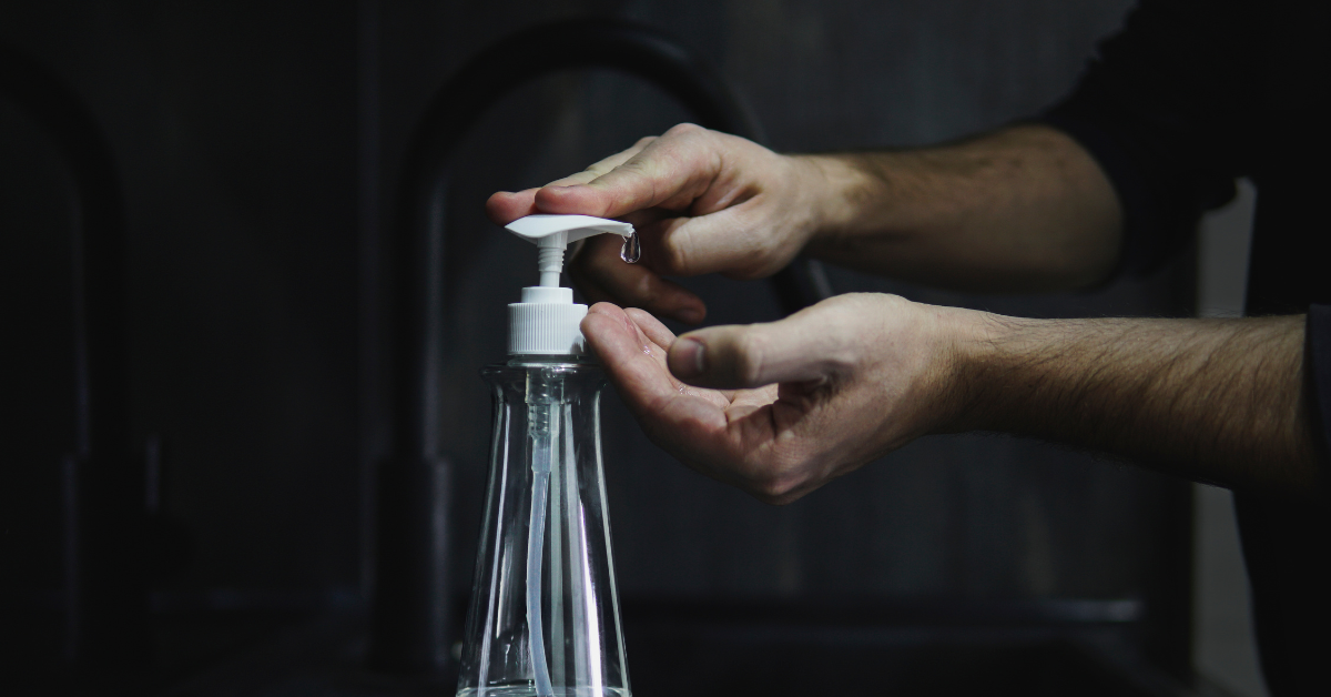 Man uses hand sanitizer in a dimly lit room