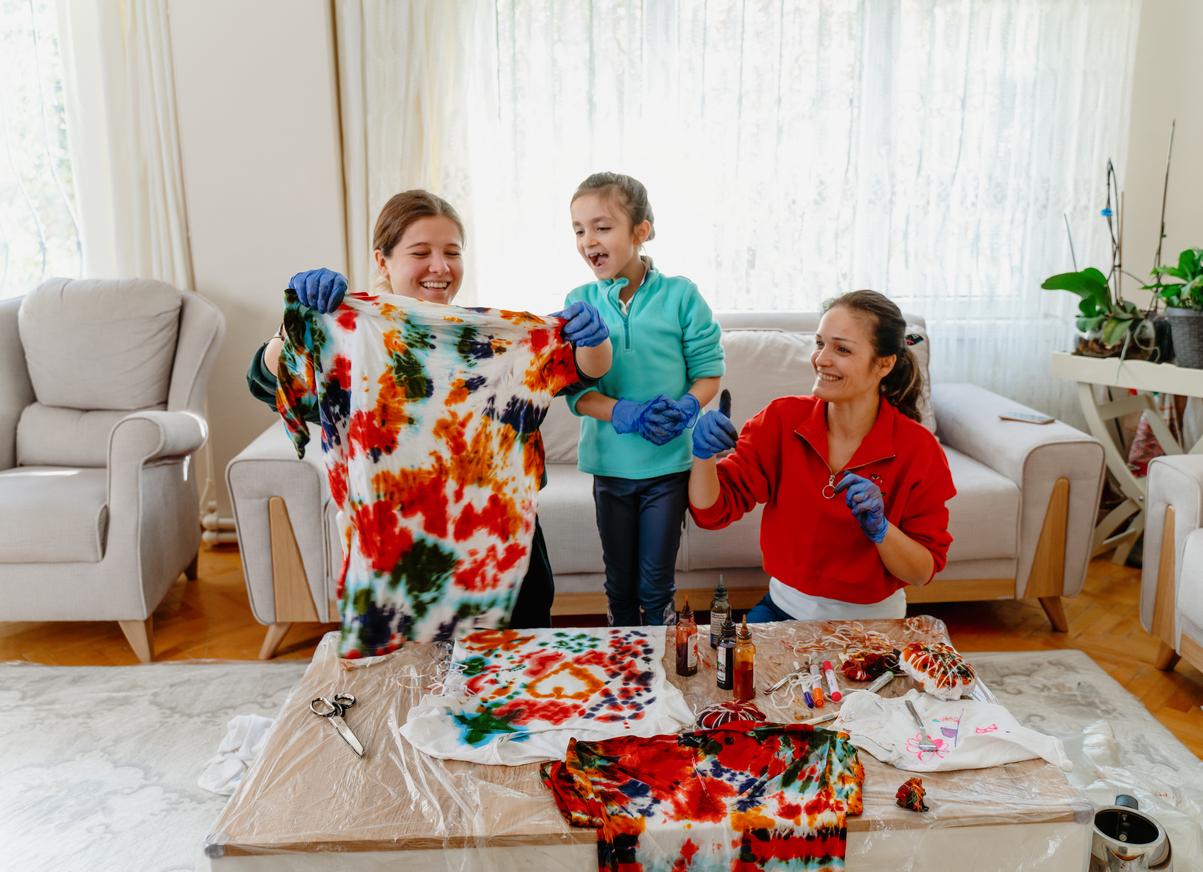 A family makes tie dye clothes together in the living room on a table beside the couch.