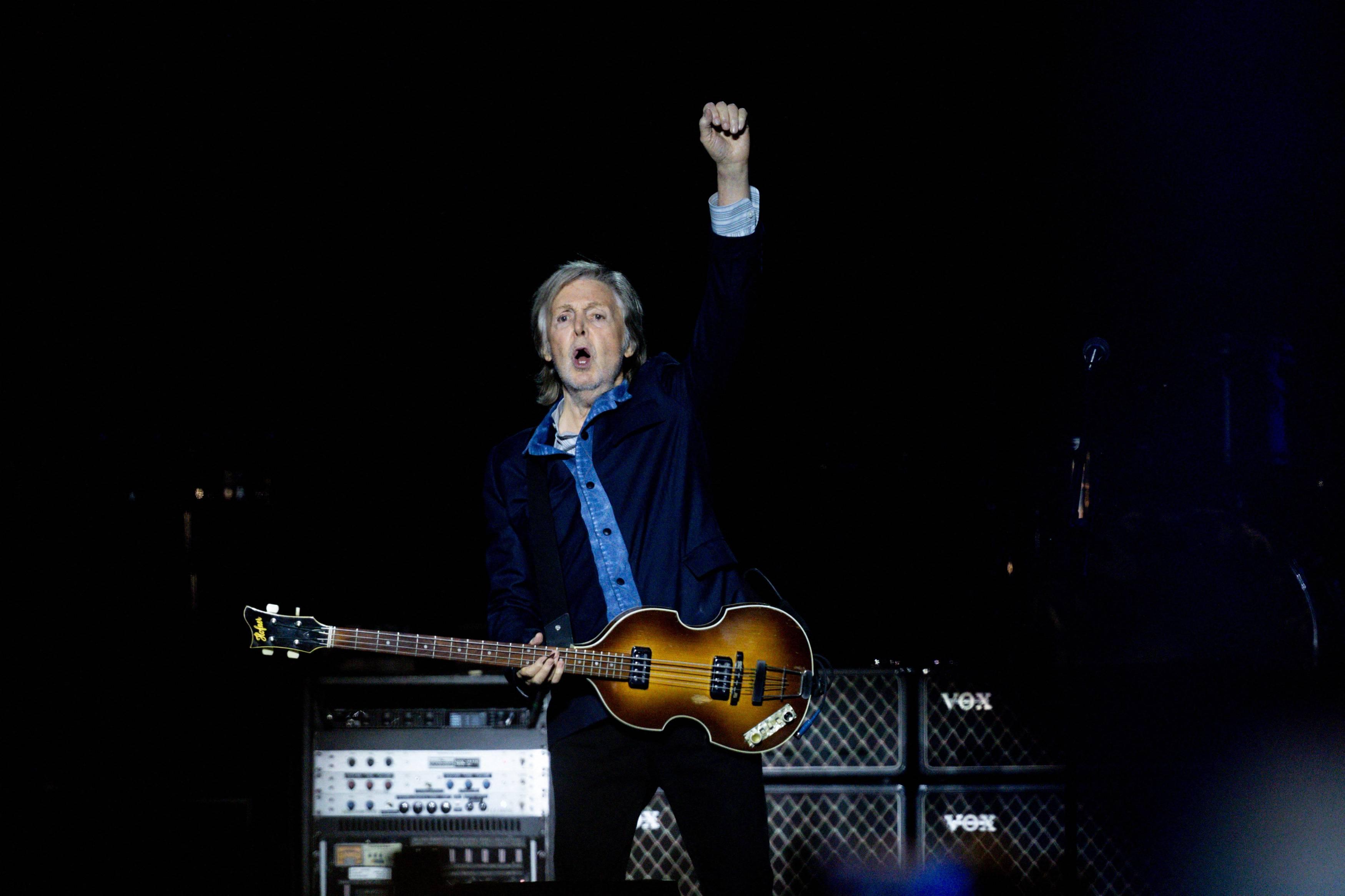 Paul McCartney raises his hand in the air while performing in Madrid in Dec. 2024.