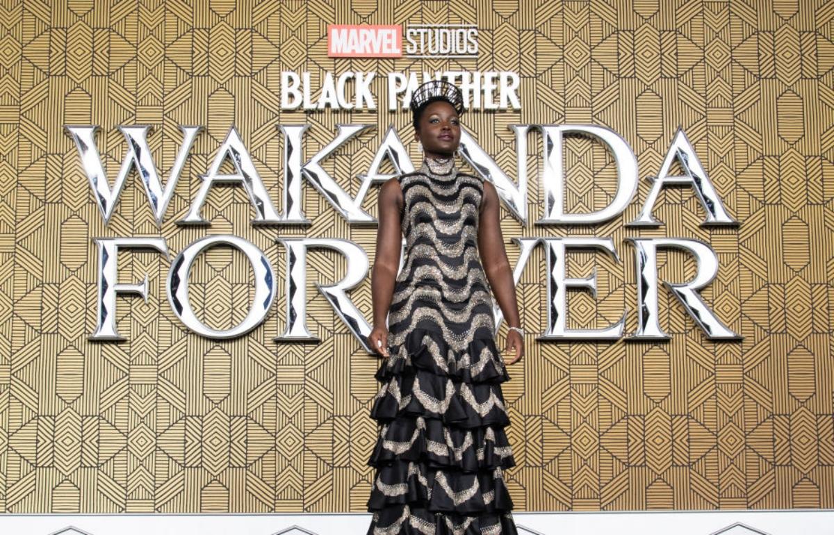 Lupita Nyong'o in ball gown with Wakanda Forever title behind her