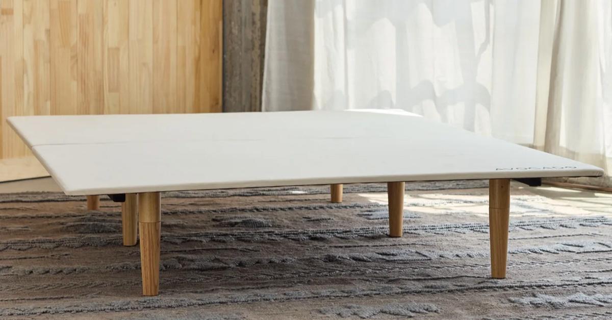 white platform bed base with wooden legs on a rug