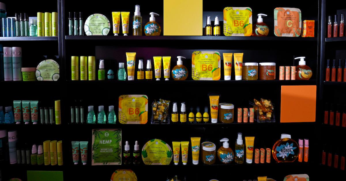 On black shelves, various makeup and beauty products in green, yellow, and orange tones are lined up