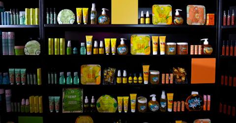 On black shelves, various makeup and beauty products in green, yellow, and orange tones are lined up