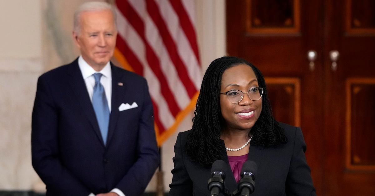 Ketanji Brown Jackson speaks at a podium with U.S. President Joe Biden behind her.