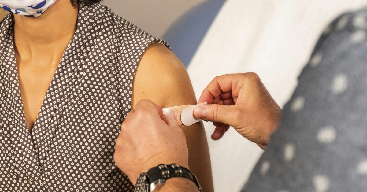 A woman gets a bandaid on her arm after receiving a vaccine