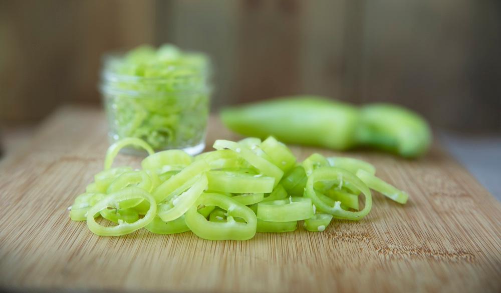 Chopped banana peppers on a wooden cutting board.