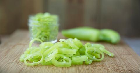Chopped banana peppers on a wooden cutting board.