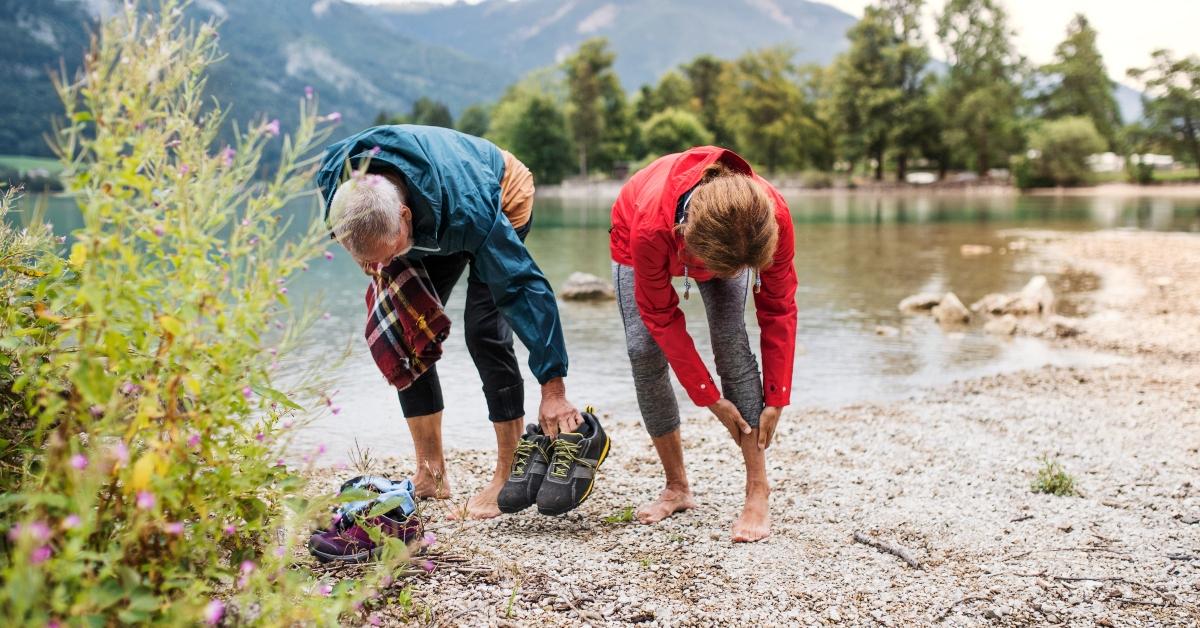 Photo of hiking couple removing shoes by a lake