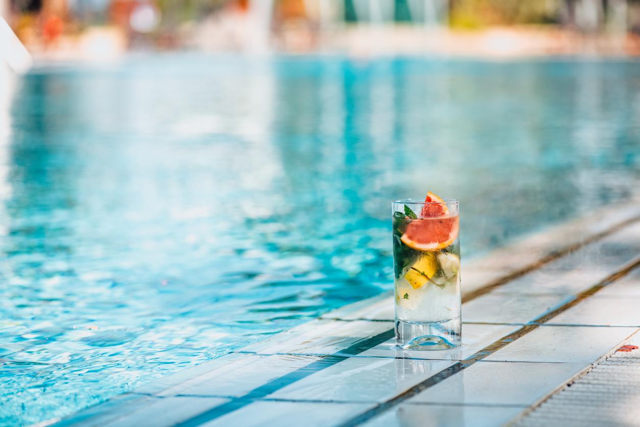 A drink sitting by the edge of a pool. 