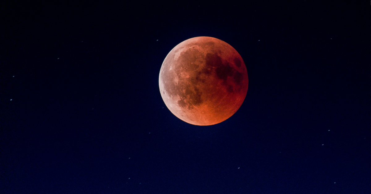 Stars are visible in the night sky as the blood moon