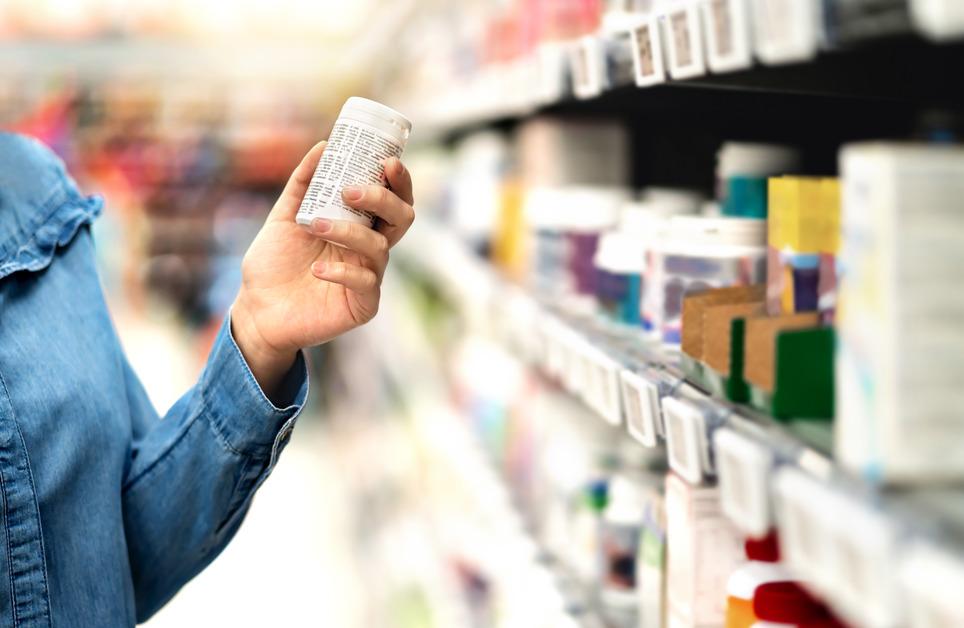 Customer in a pharmacy reading a medicine bottle.