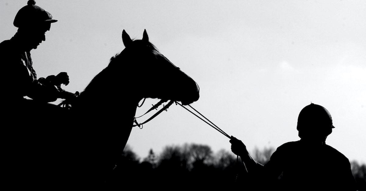 A black-and-white shot of a horse, a jockey, and their handler.