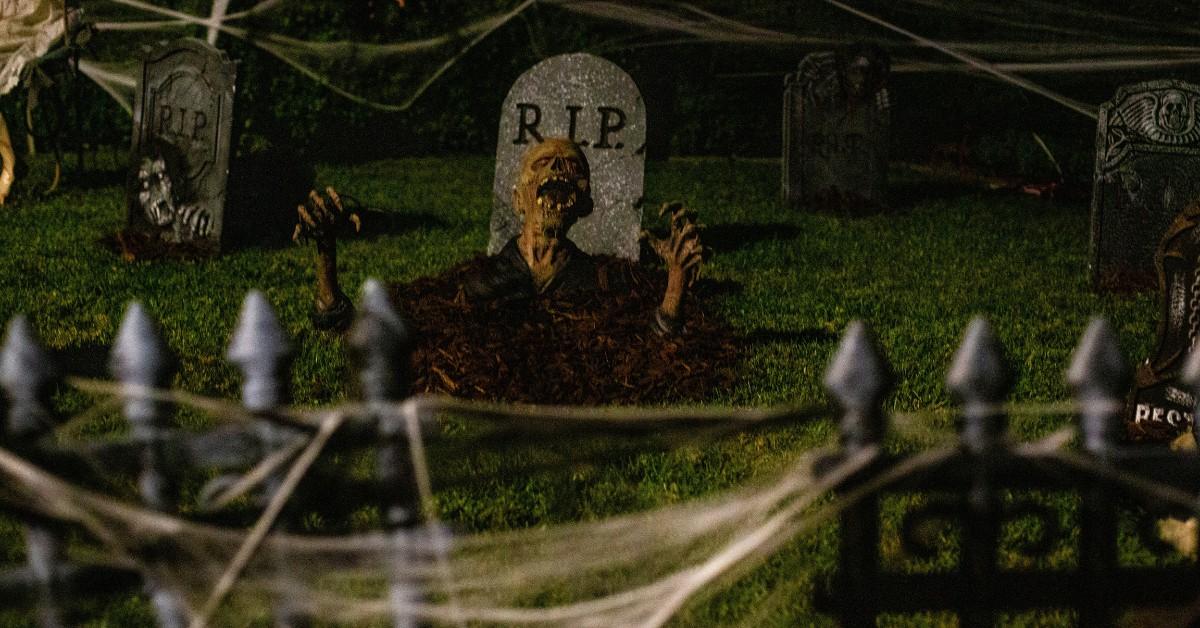 A faux skeleton is popping out of the ground as part of an elaborate Halloween display 