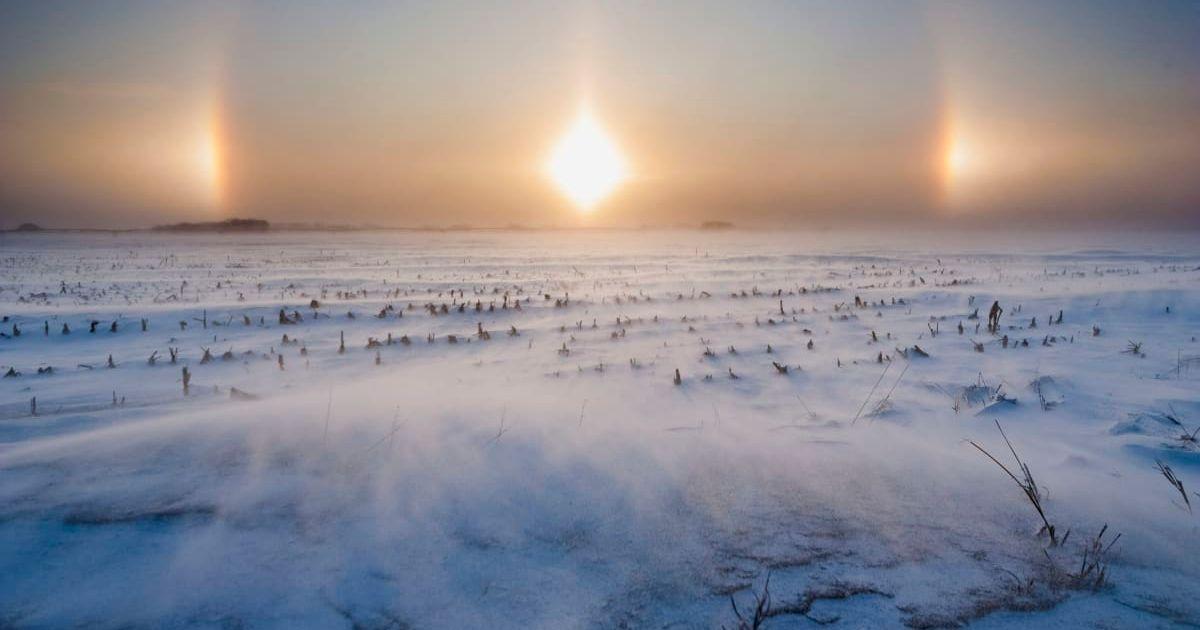 A white landscape blanketed in snow and a sundog, an optical phenomenon characterized by rainbowy patches of concentrated light (Representative Cover Image Source: Getty Images | Mike Hollingshead)