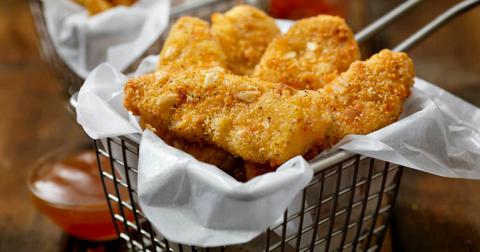 Basket of crispy vegan chicken nuggets with dipping sauce on the side.