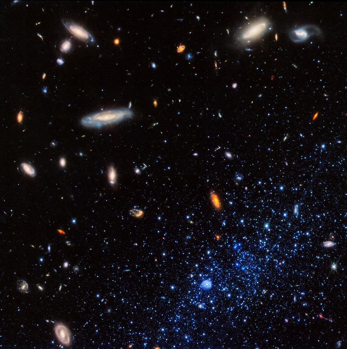 The blue stars from the Leo P Galaxy appear in the bottom right of a photo taken by the James Webb Space Telescope, featuring the oranges, blues, yellows, and whites in space.