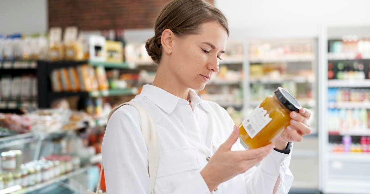 Woman looks at the label of a jar of honey at the grocery store. (Representative Cover Image Source: Freepik | freepik)