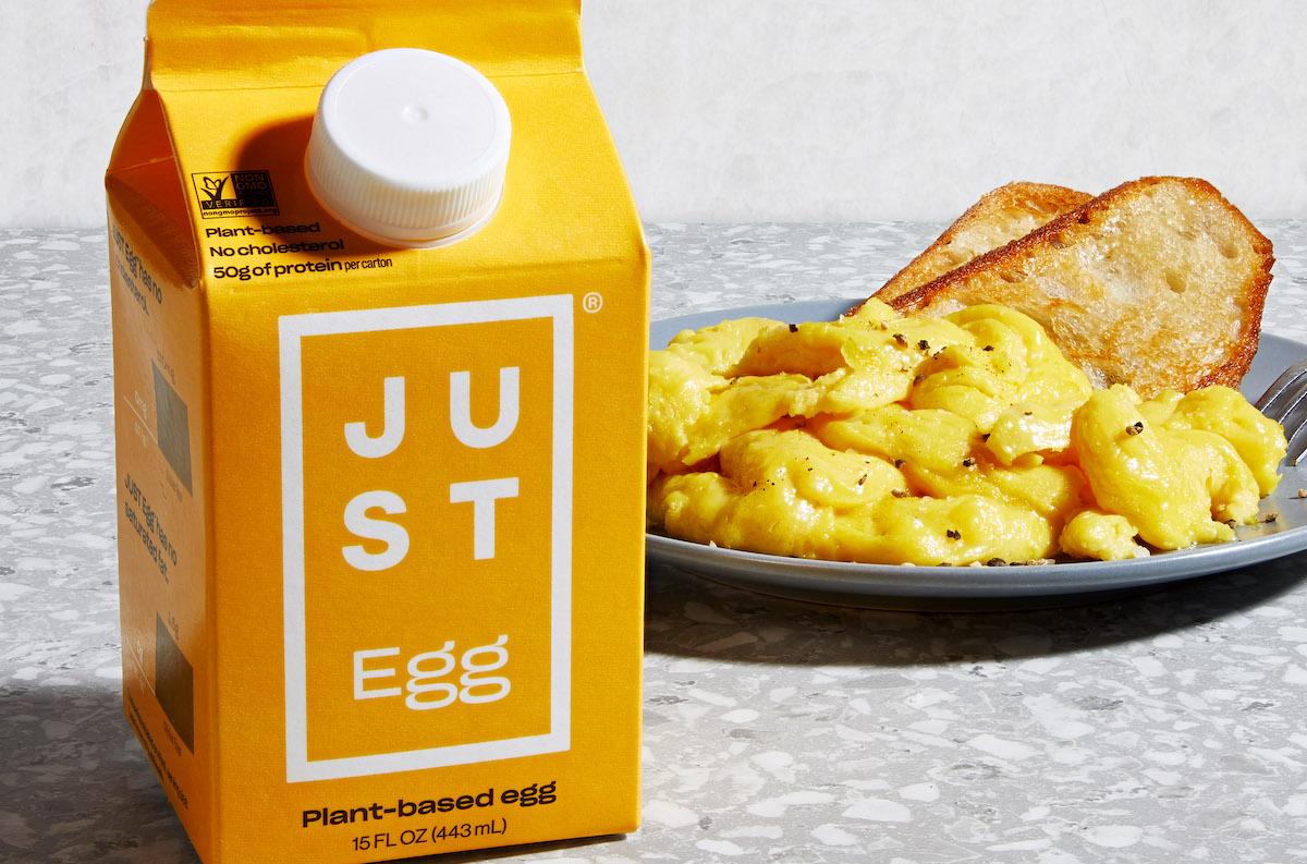 Yellow carton of Just Egg on a counter, next to a plate of scrambled plant-based eggs and toast.