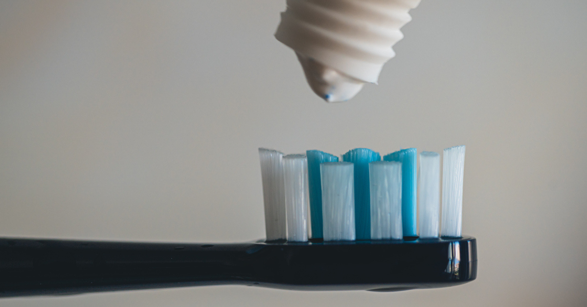 A drop of toothpaste hovers above a toothbrush 