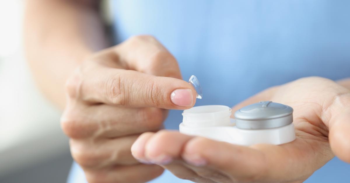 A hand putting contacts into a contact case. 