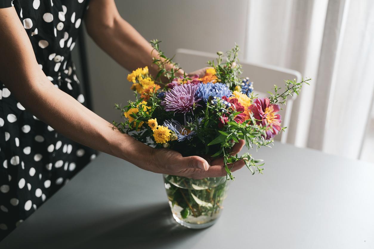 Close up of a person touching colorful flowers in a glass vase