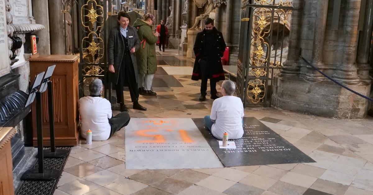 Alyson Lee and Di Bligh sitting on Charles Darwin's grave after spray painting it in protest. 