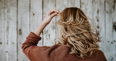 back of woman's head with blond hair and a brown sweater