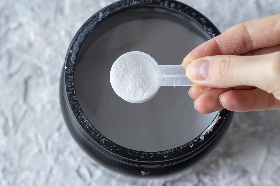 A close-up of a measuring spoon full of white BCAA powder. 