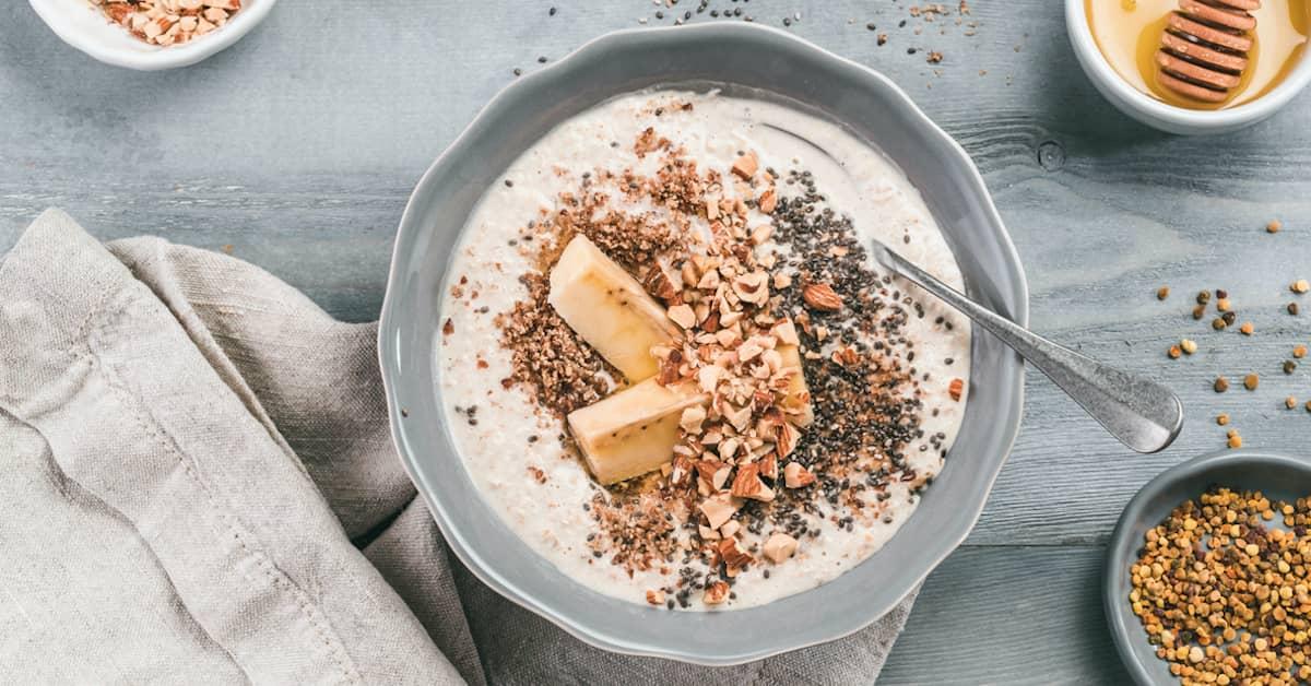 Delicous bowl of porridge topped with chopped nuts, chia seeds and sliced fruit.