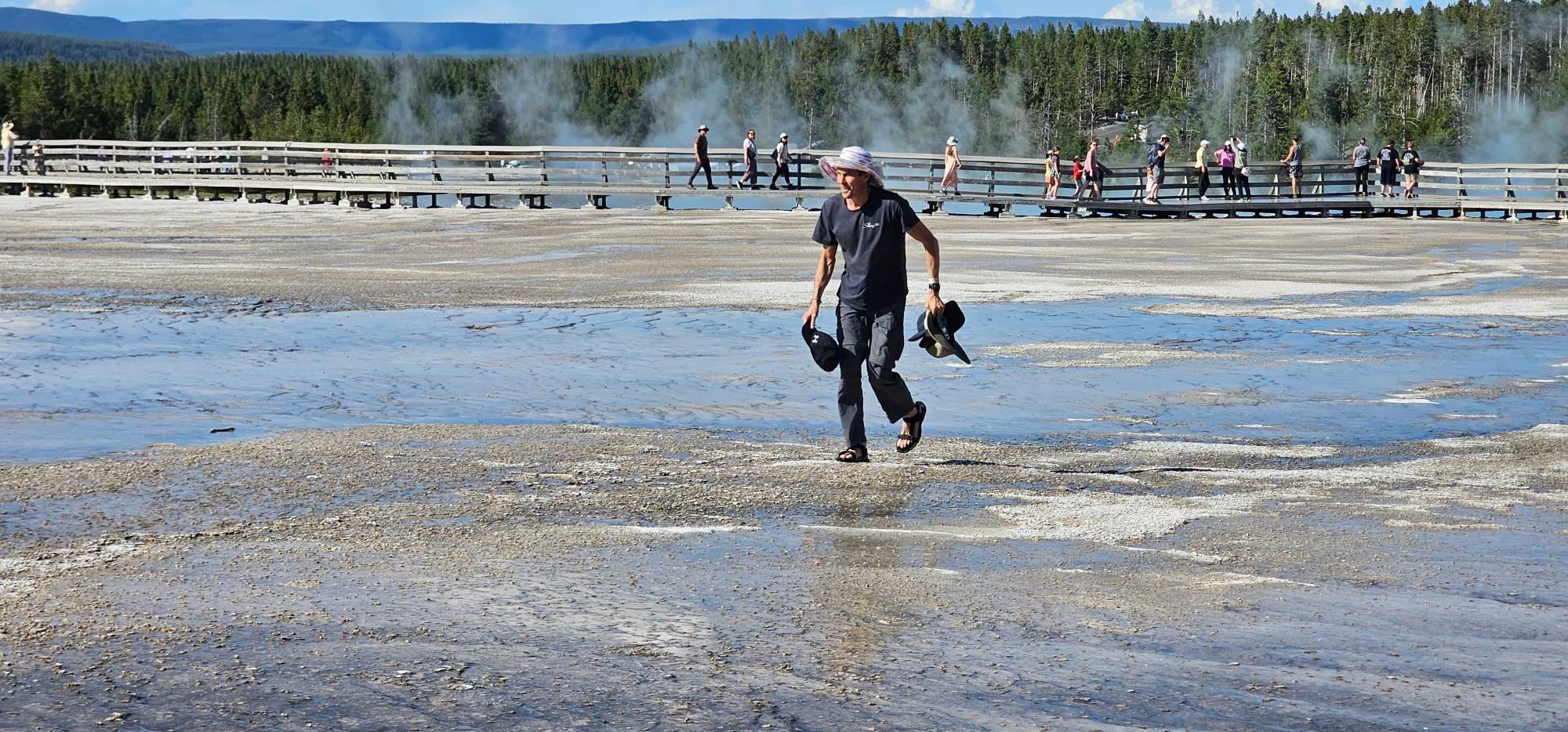 A tourist in flip-flops walks across a protected area of Yellowstone.