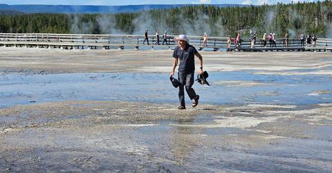 A tourist in flip-flops walks across a protected area of Yellowstone.