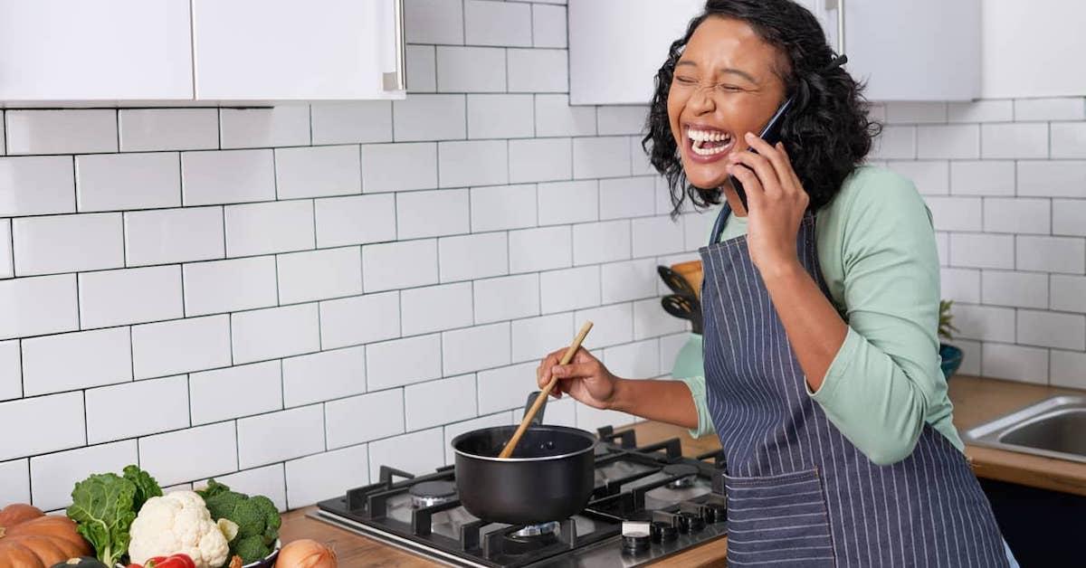 Happy person talking on the phone while cooking an easy vegan meal.