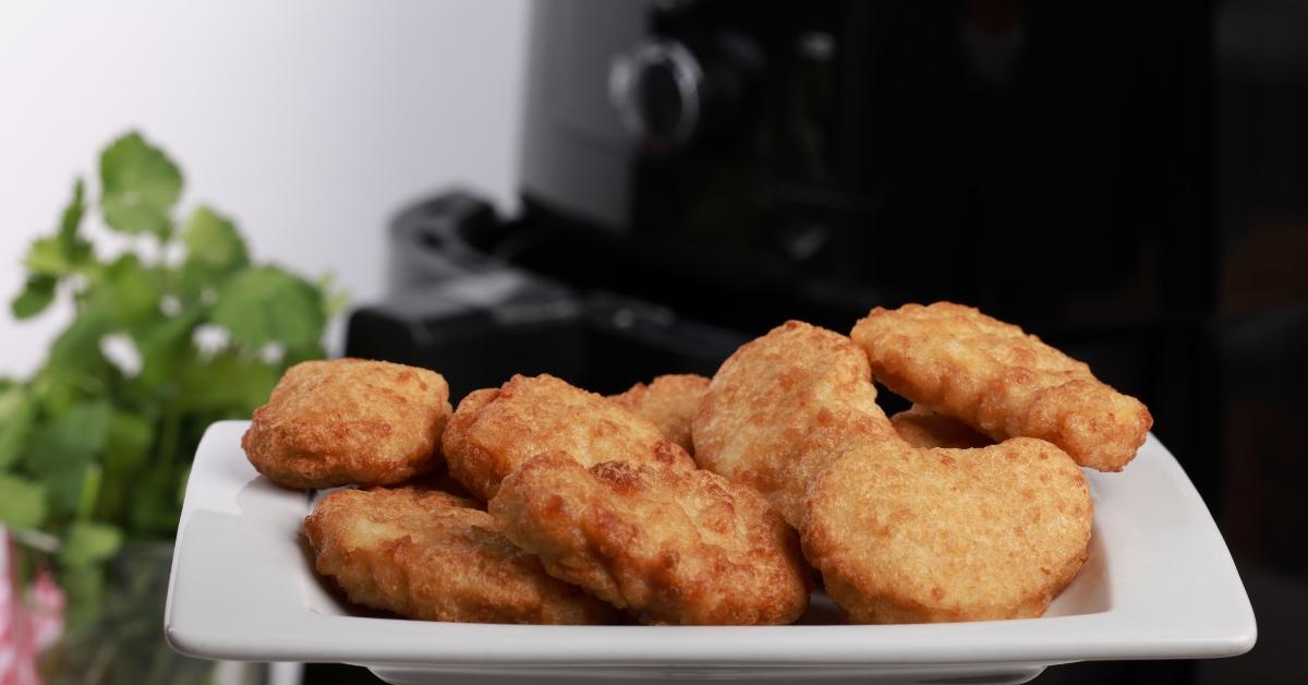 Plate of chicken nuggets in front of an air fryer. 