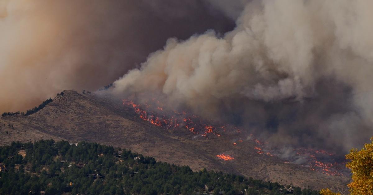 Smoke from wildfire on a mountainside in a forest. 