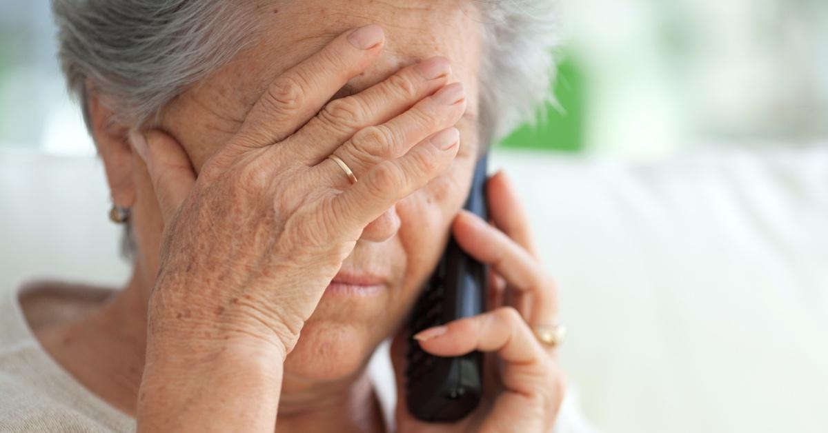 Woman with a hand over her face on the phone suffering from dementia. 