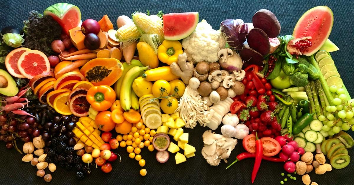 Colorful fruits, vegetables, and nuts lay against a black backdrop 