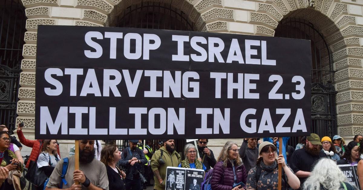 A sign reads "stop Israel starving the 2.3 million in Gaza" at a protest