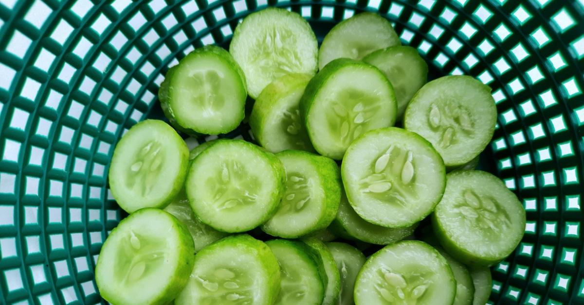 Green basket of sliced cucumbers. 