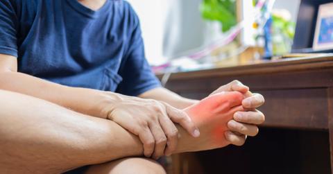 A man clutches his foot in pain.