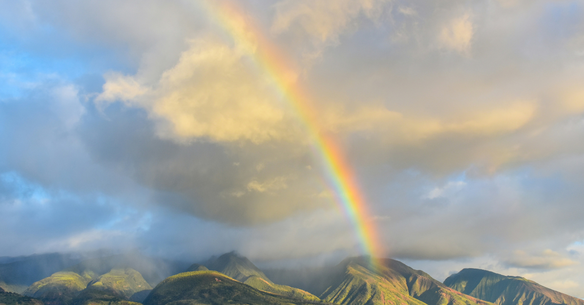 A rainbow appears over a mountain range