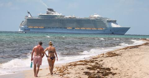 Couple walking on the beach with a cruise ship in the distance.