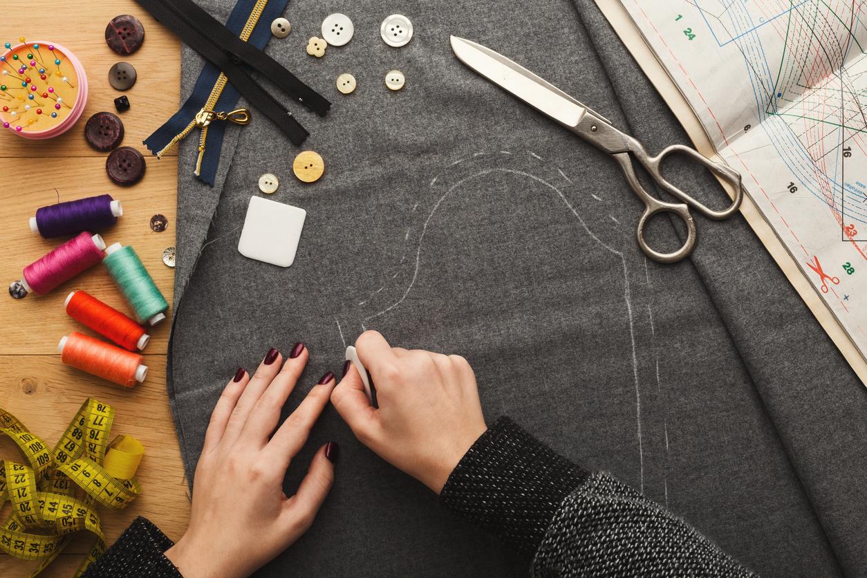 Close up of a pattern being drawn on black fabric by someone for a sewing project.