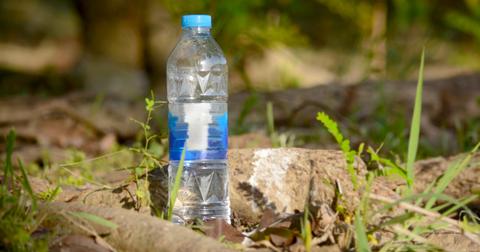 Photo of half-full water bottle sitting in rocks and grass