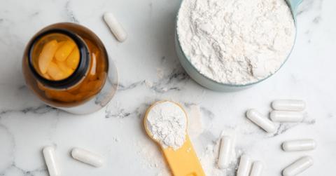 Powdered creatine supplements in a measuring cup and measuring spoon, and a jar of capsules