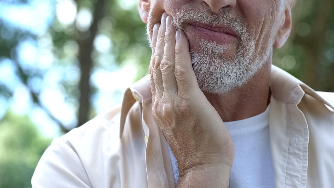 Person touching cheek with hand to indicate pain or discomfort