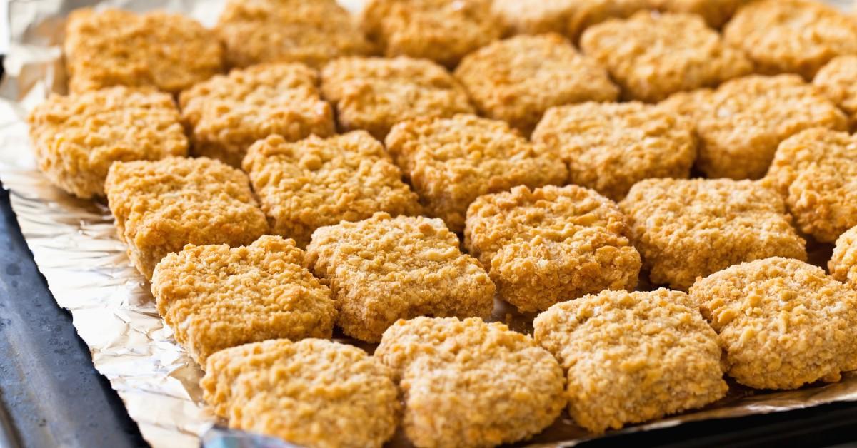 A tray of frozen chicken nuggets about to go into the oven