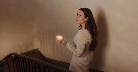 Photo of sustainable interior decorating YouTuber MaCenna Lee walking down the stairs holding an Auden Lueur candle