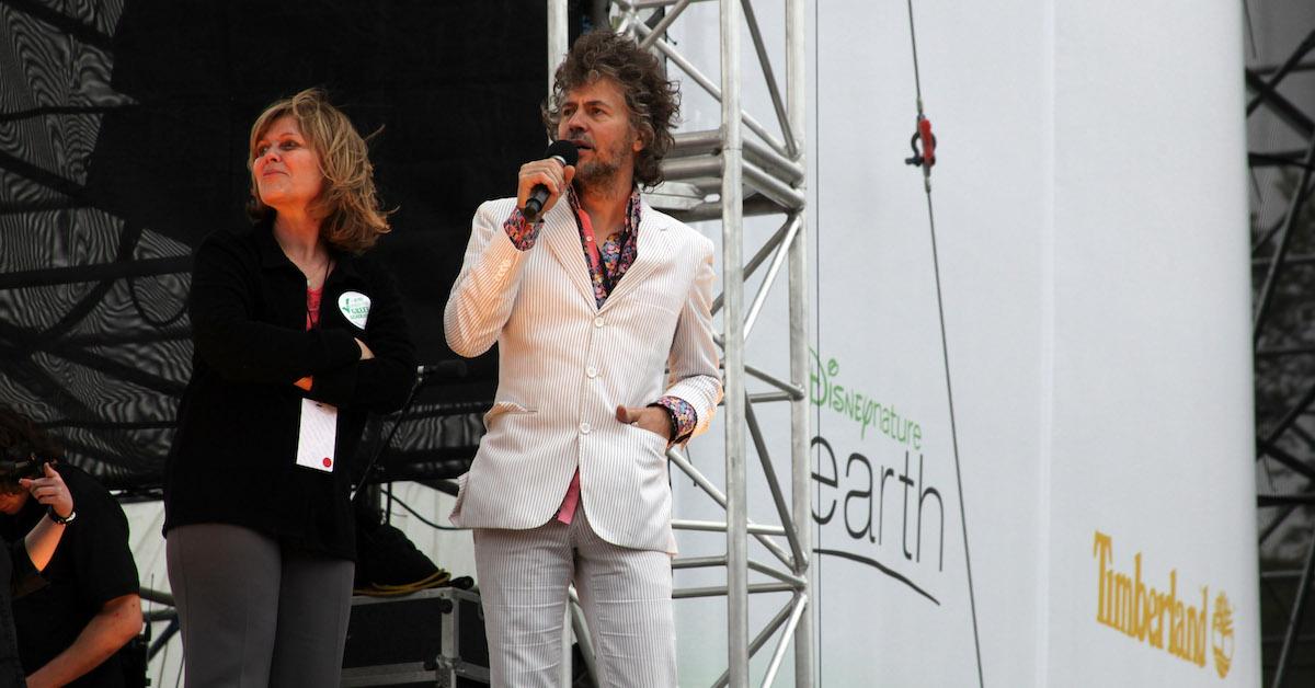 Kathleen Rogers and Wayne Coyne stand on stage, looking off to their right